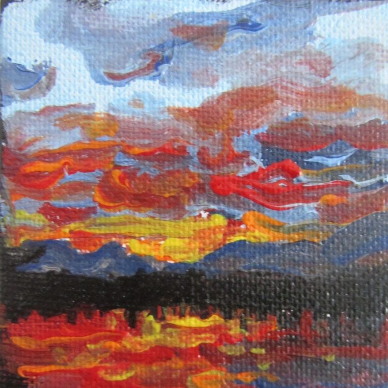 Farbenfroher Sonnenuntergang mit roten, orangen und blauen Wolken über einem dunklen Horizont.