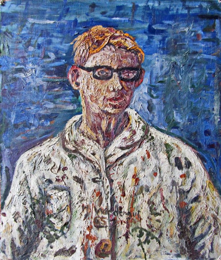 Porträt eines Mannes mit blonden Haaren und Brille, in einem gemusterten Hemd vor blauem Hintergrund.