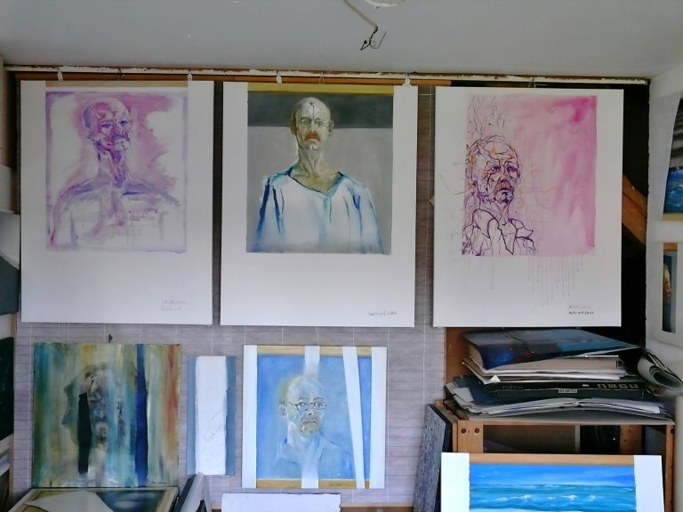Drei Porträts an der Wand, umgeben von weiteren Gemälden und Kunstmaterialien.